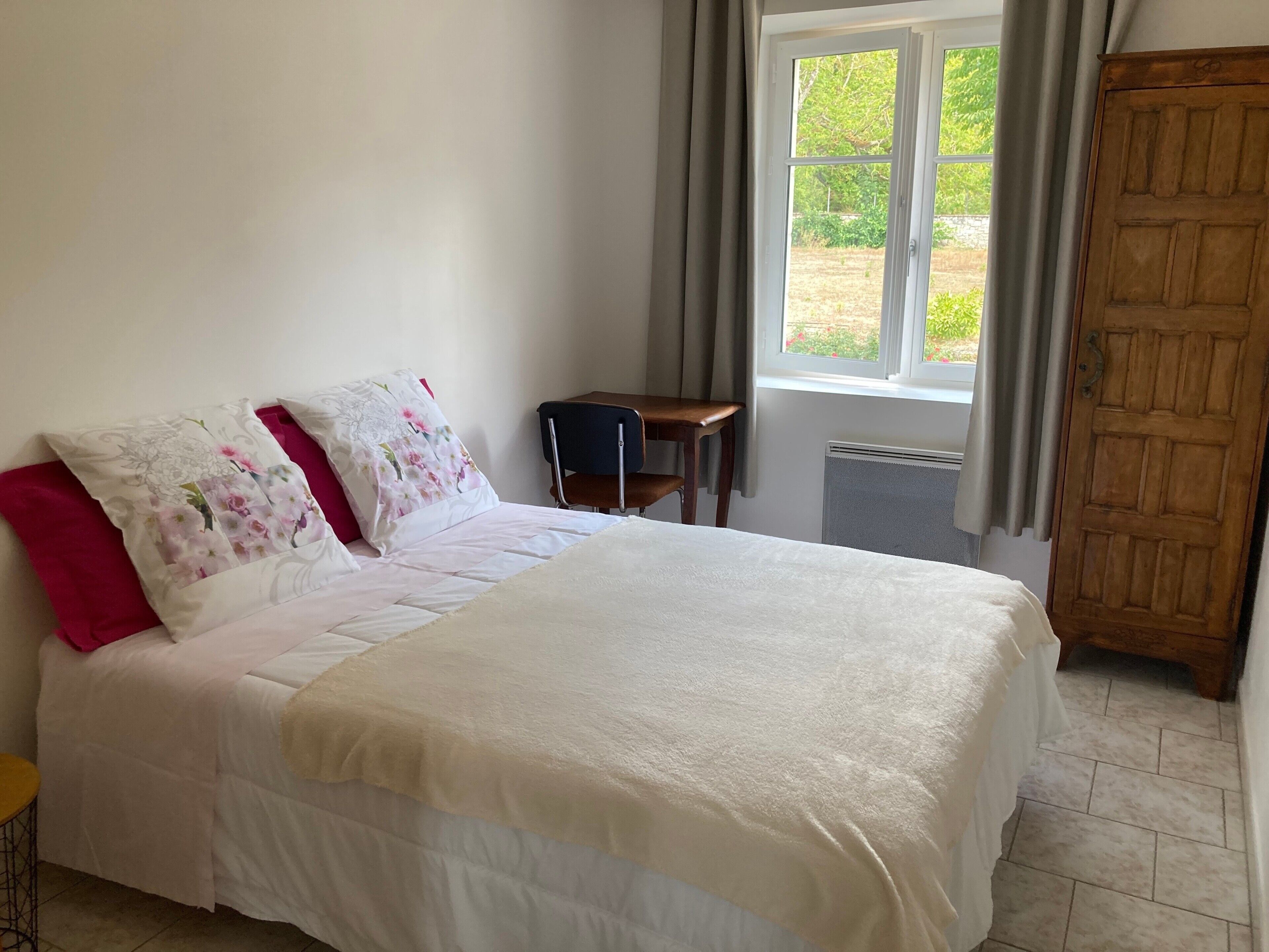 A bedroom with a bed, a chair, a window, and a door.