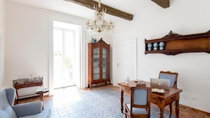 A room with a dining table, chairs, a chandelier, a cabinet, and a laptop. - Palazzo Cacace Relais (Meta)
