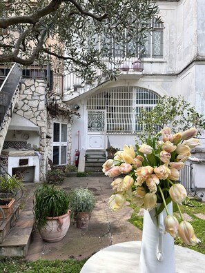 Un patio con una escalera de piedra, una puerta blanca y una ventana con barandales decorativos.