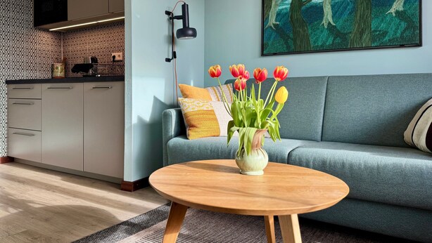 Un salon moderne avec un canapé, une table basse ronde en bois et un vase de tulipes.