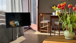 Une pièce avec une table en bois, un vase de tulipes, un téléviseur et une chaise.