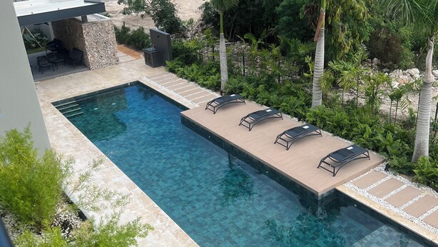 A rectangular swimming pool with clear water, surrounded by a stone deck and equipped with lounge chairs. - Beautiful 1-Bedroom Apt en las Canas punta cana. (Punta Cana)