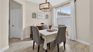 Comedor con mesa preparada para cuatro personas, un candelabro y vistas al exterior.