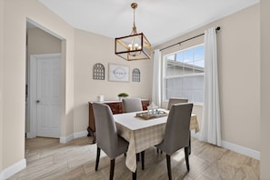 A dining room with a table set for four, a chandelier, and a view of the outside. -     Family-Friendly PSL Vacation Home Near Clover Park & Beaches (Port Saint Lucie)