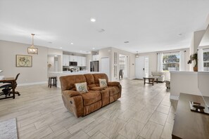 A spacious living area with a brown sofa, a dining table, and a kitchen in the background. -     Family-Friendly PSL Vacation Home Near Clover Park & Beaches (Port Saint Lucie)