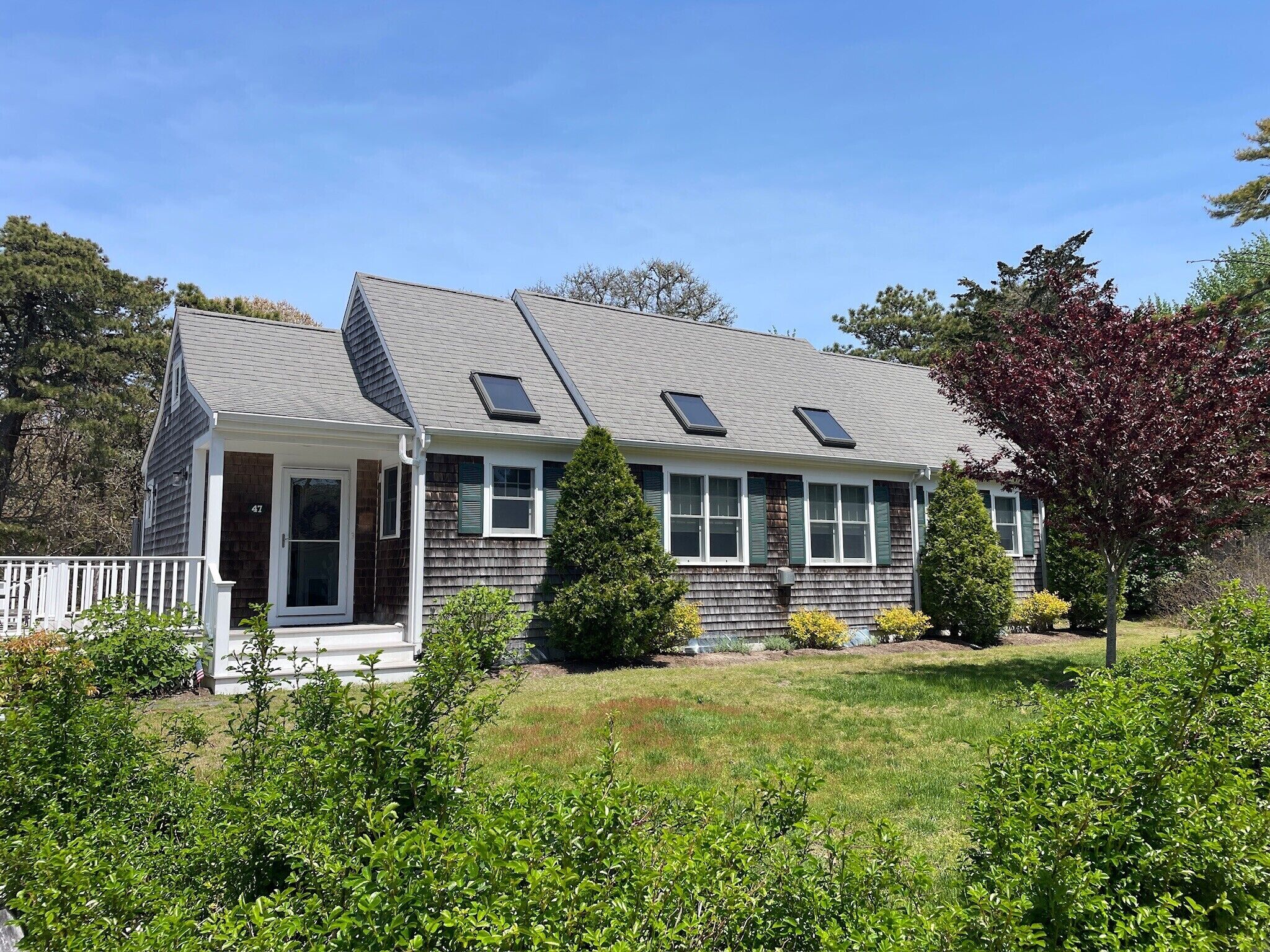 A two-story house with a porch, a small deck, and a well-maintained lawn.