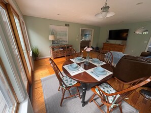 A dining area with a wooden table set for four, surrounded by chairs with patterned cushions. - Relaxing Cape Escape • Family Retreat • Walk to Beach • 6 beds • Sleeps 8 (Chatham)