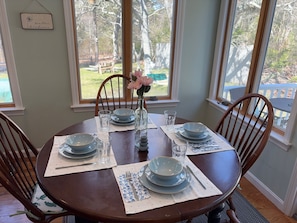 A dining table set with blue plates, glasses, and a vase with flowers.
