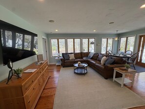 A spacious living room with a large sectional sofa, a coffee table, and a wooden dresser. - Relaxing Cape Escape • Family Retreat • Walk to Beach • 6 beds • Sleeps 8 (Chatham)