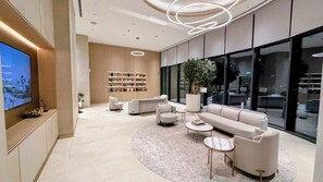 Una sala de estar moderna con un televisor grande, sofás, una mesa de centro y una estantería.