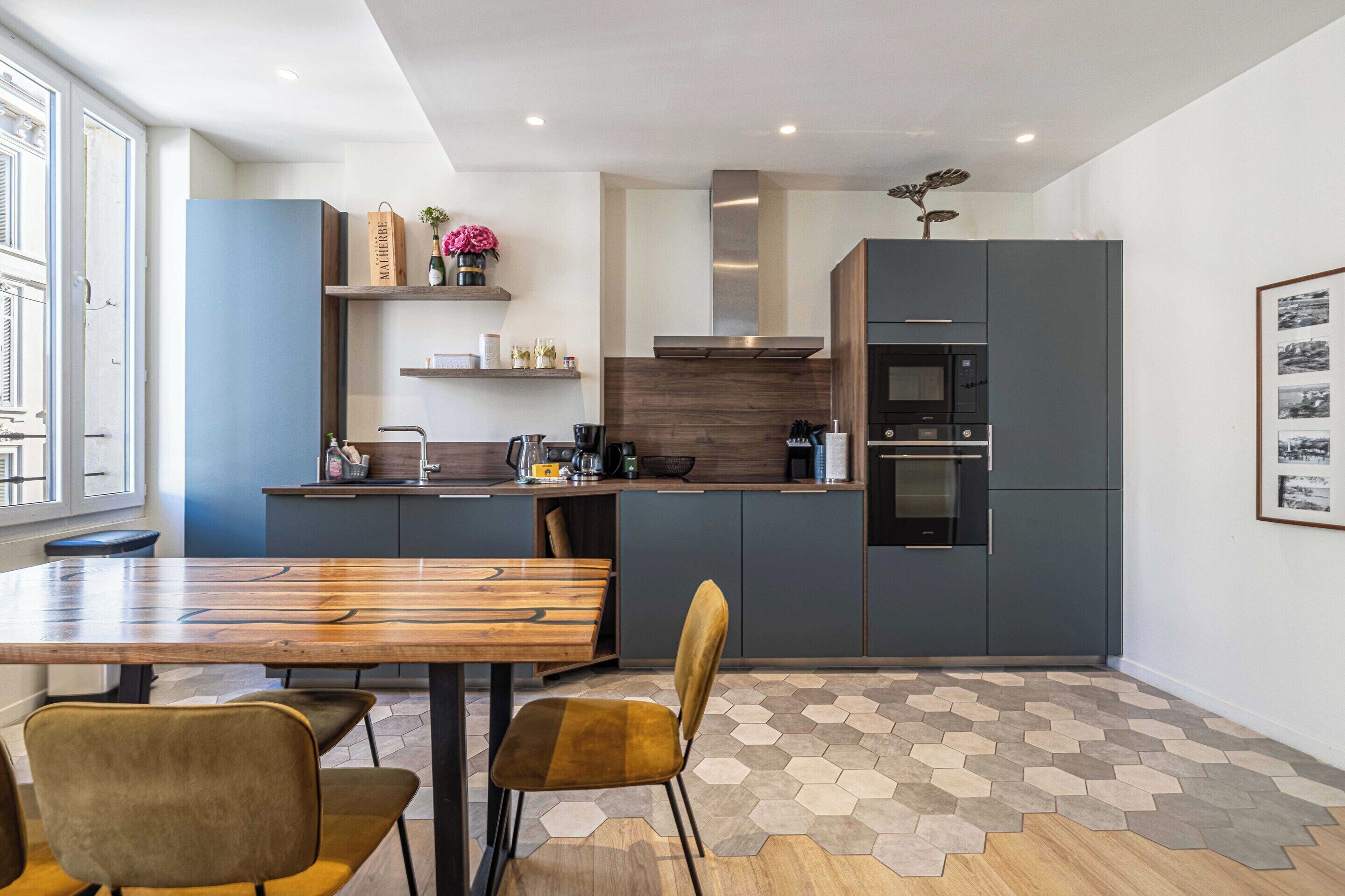 A modern kitchen with a wooden dining table, two chairs, and a built-in oven.