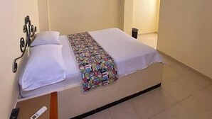 A hotel room with a bed, a TV, a painting, and an air conditioning unit. - Hotel Terranova SM (Santa Marta)