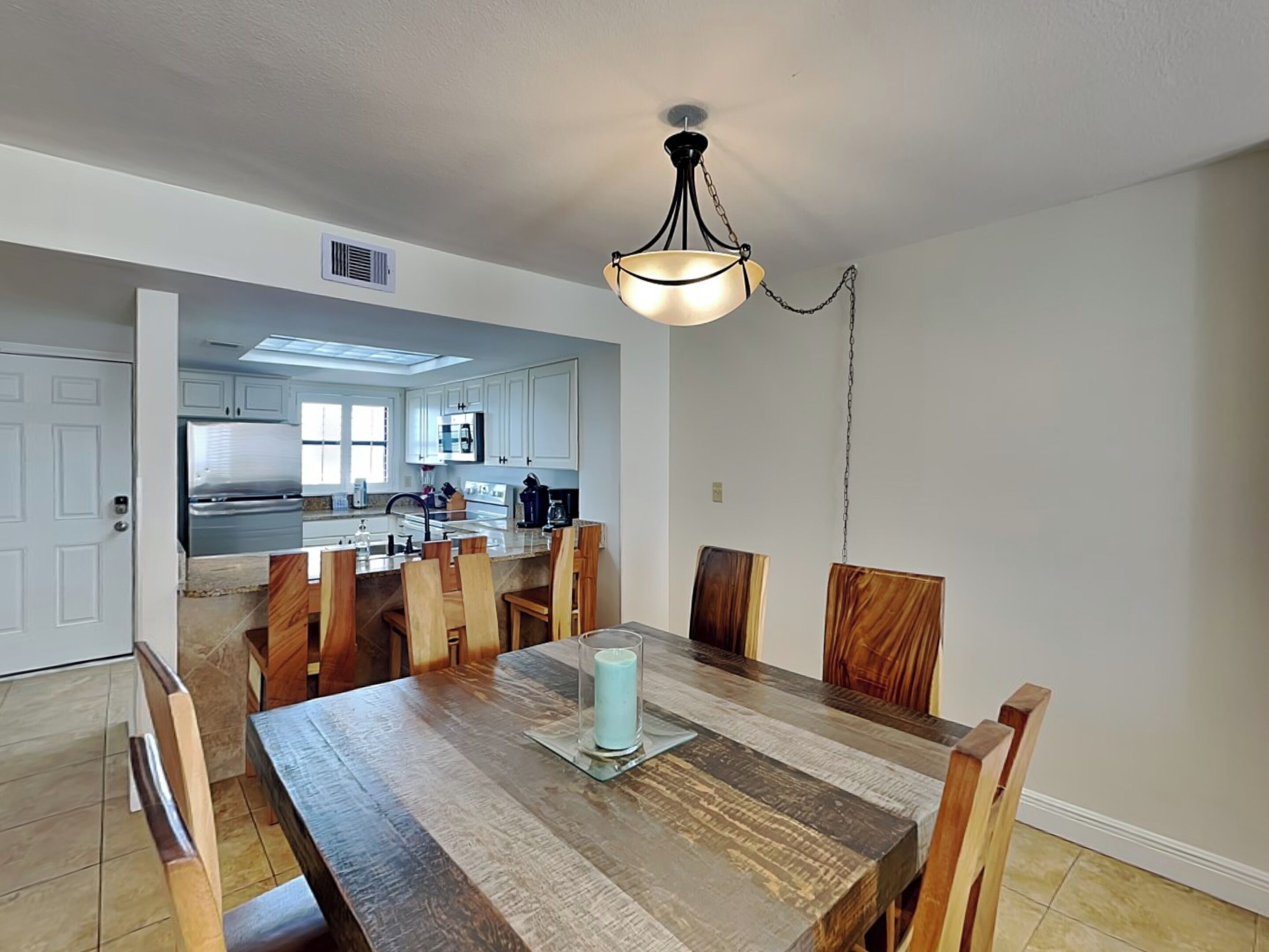 A dining area with a wooden table, chairs, and a hanging light fixture.