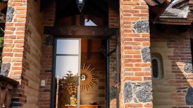 A traditional brick building with a wooden gable roof, a glass door entrance, and a small porch area.