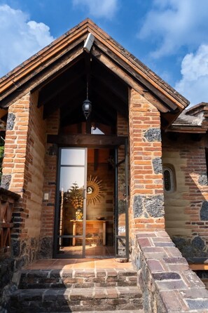 A traditional brick building with a wooden gable roof, a glass door entrance, and a small porch area. - Scenic Cabin Retreat in Breathtaking Tepoztlán (Tepoztlán)