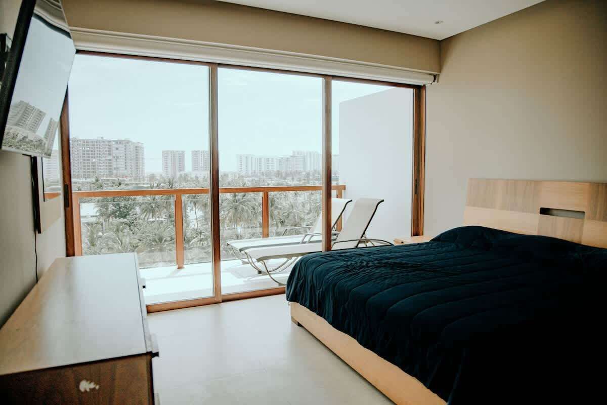 Une chambre avec une grande fenêtre, un lit, un bureau et une chaise.