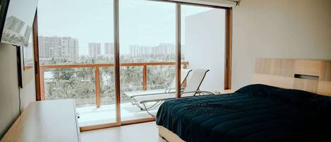 Une chambre avec une grande fenêtre, un lit, un bureau et une chaise.