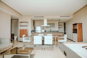 A modern hotel room with a kitchenette, a dining area with white chairs, a sofa, and a glass coffee table. - Spacious 3BR w/ Terrace in La Isla Acapulco (Acapulco de Juárez)