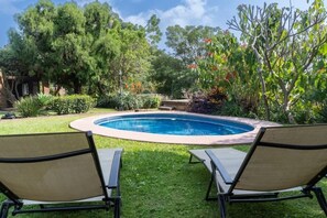 Ein Garten mit Swimmingpool, zwei Liegestühlen und verschiedenen Pflanzen.
