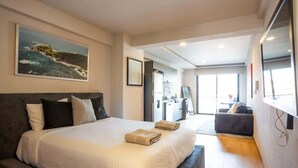 A modern hotel room with a large bed, a desk, and a view of the sea. - Chic Roma Norte Studio w/ Private Balcony (Mexico City)