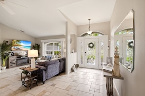 A living room with a sofa, a lamp, a fireplace, and a television. - Paradise Skye Golf, Pool & Beach Retreat (Rotonda West)