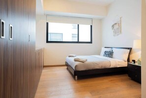 A bedroom with a bed, a window, a wardrobe, and a wall-mounted artwork. - Roma Norte 3BR | Pool, Gym & Great Vibes (Ciudad de México)