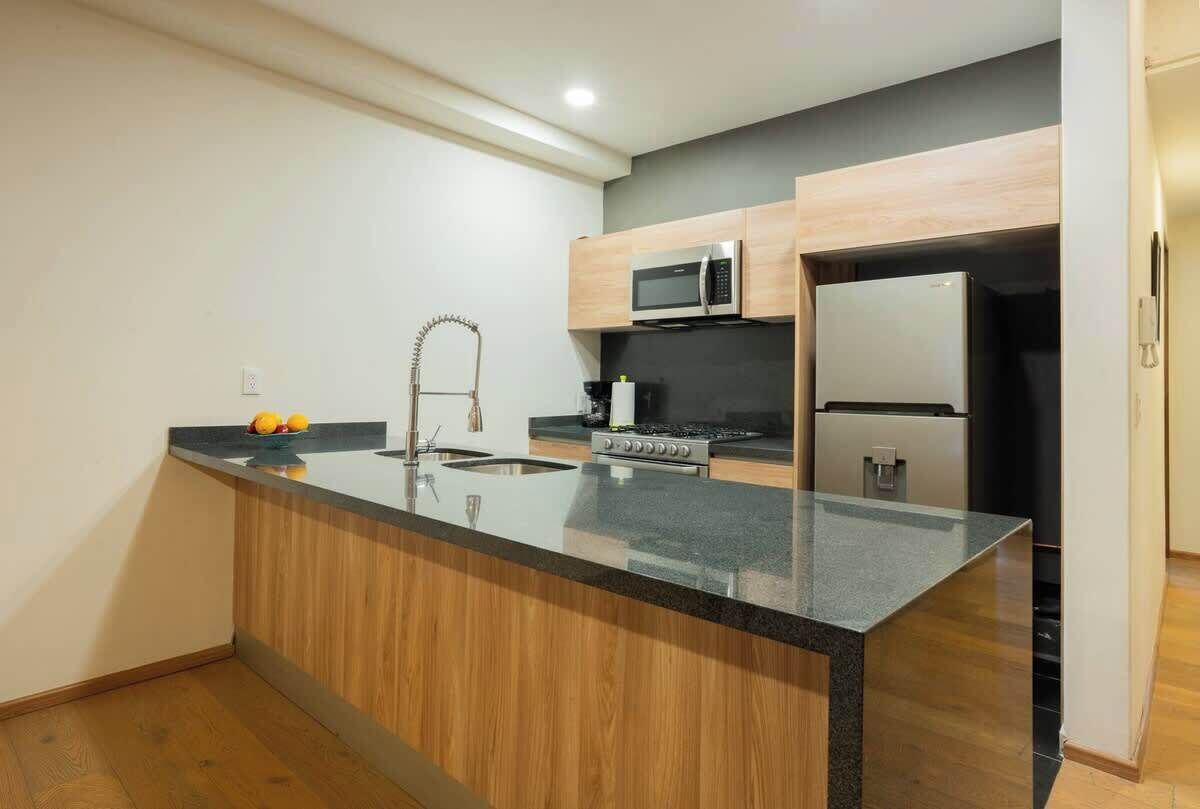 A modern kitchen with a central island, stainless steel appliances, and wooden cabinetry.