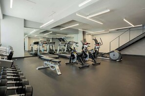 A gym with exercise equipment, a bench, and a staircase. - Roma Norte 3BR | Pool, Gym & Great Vibes (Ciudad de México)