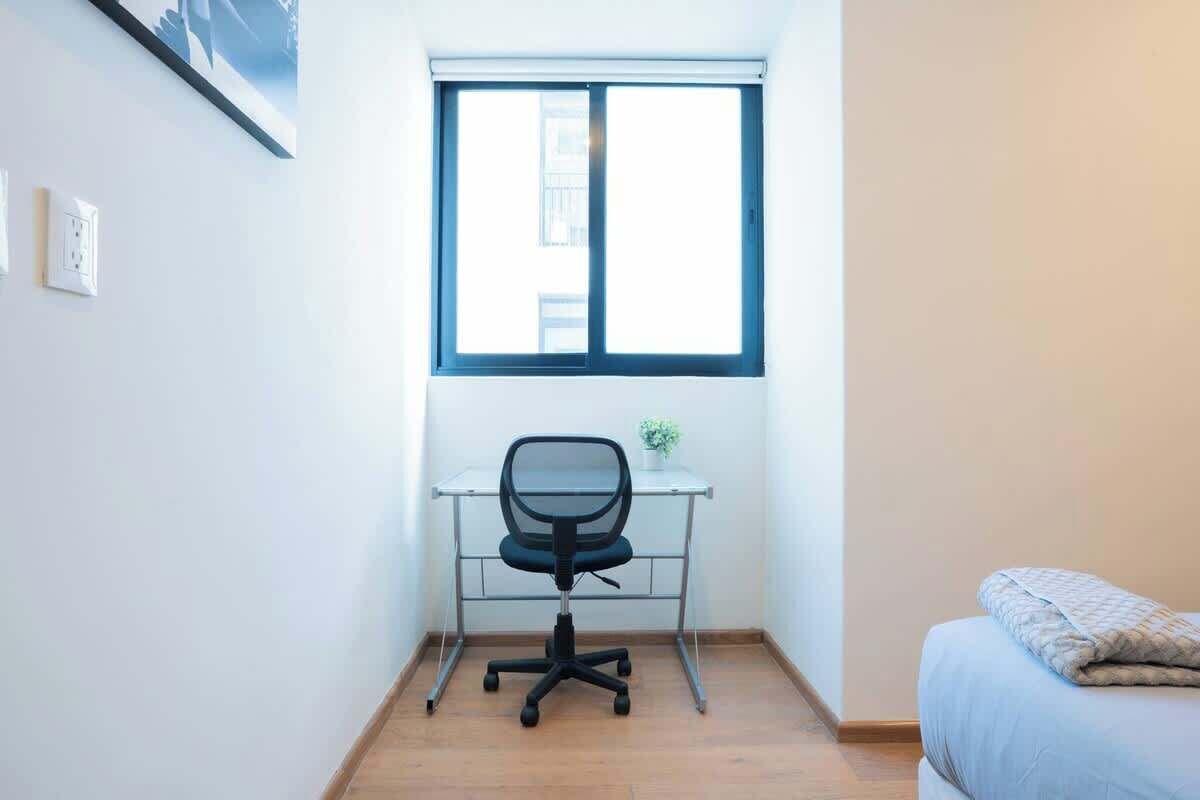 Une petite pièce comprenant un bureau, une chaise et un lit.