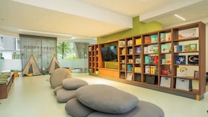 Een moderne bibliotheek met een groot boekenrek, een zithoek en uitzicht op het omliggende landschap.