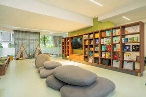 Eine moderne Bibliothek mit einem großen Bücherregal, einer Sitzgelegenheit und Blick ins Freie.