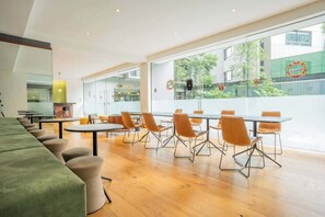 Ein moderner Konferenzraum mit Glaswänden, Holzboden und einem langen, grünen Sofa.