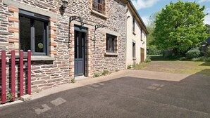 Un bâtiment en pierre avec une porte, des fenêtres et une clôture rouge.