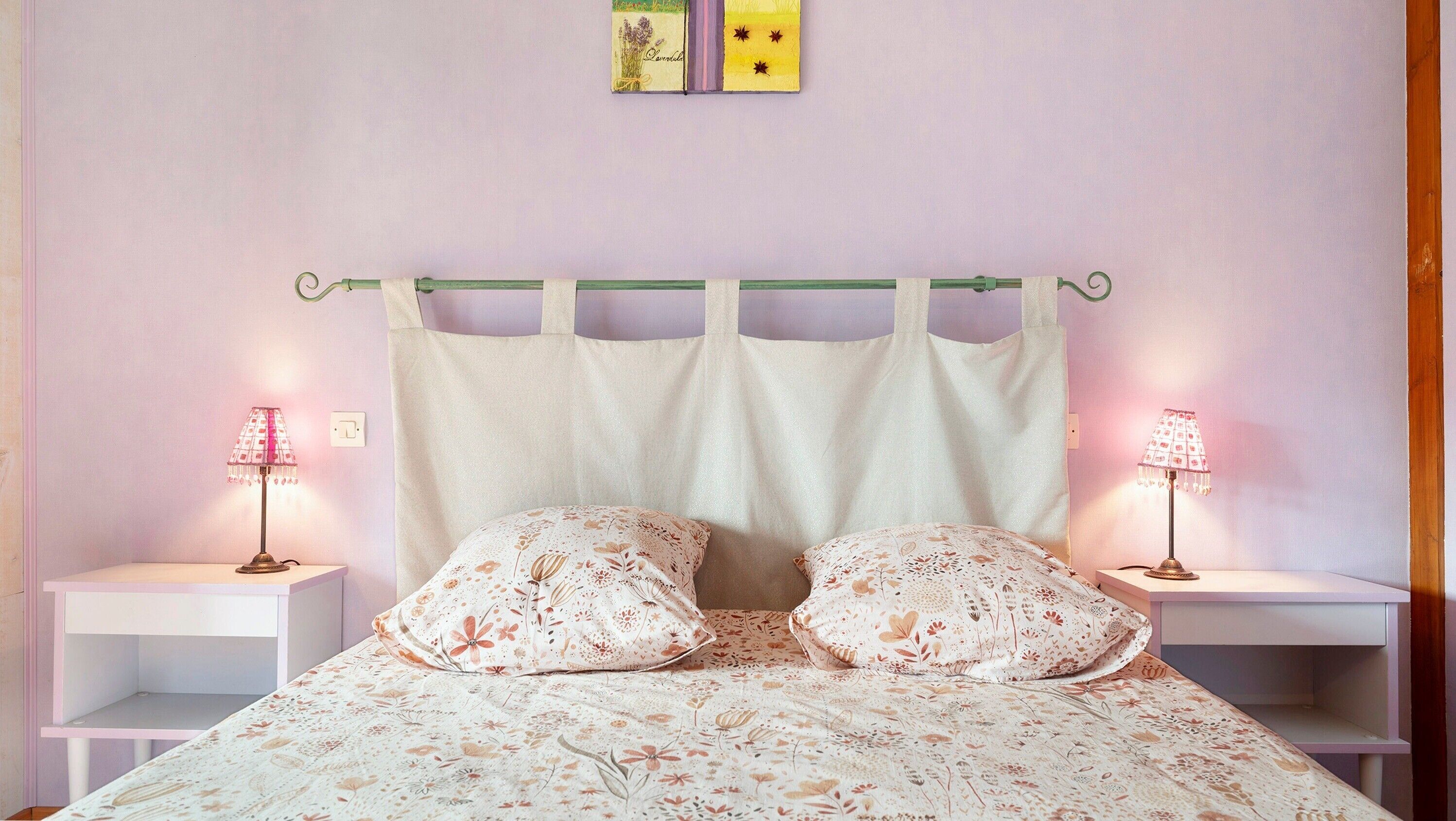 Une chambre à coucher avec un lit, deux tables de chevet et deux lampes fixées au mur.