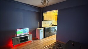 Ein Wohnzimmer mit Fernseher, kleinem Kühlschrank und einer Couch.