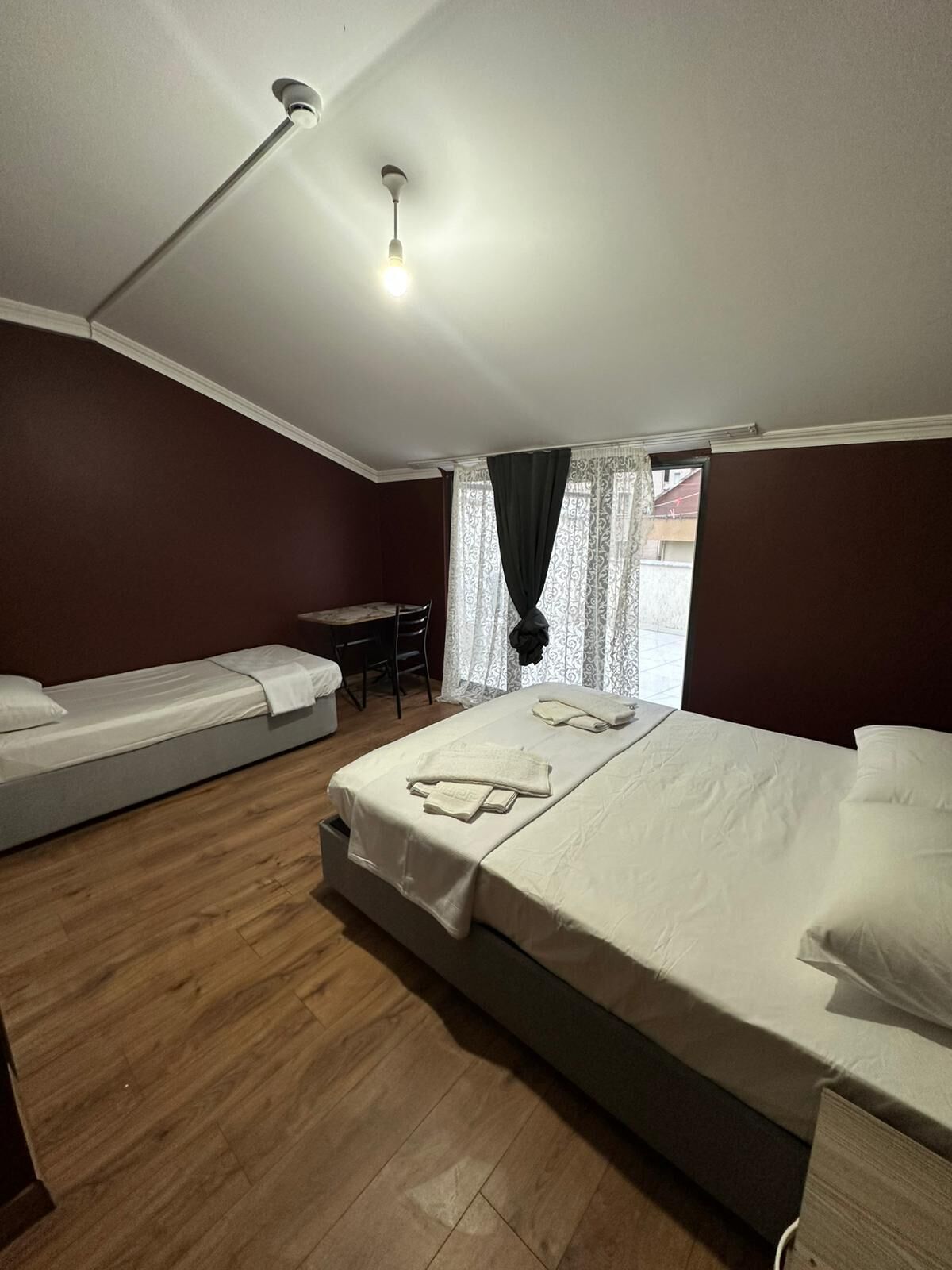 A bedroom with a large bed, a smaller bed, a desk, and a chair.