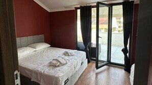 Ein Schlafzimmer mit Bett, Deckenventilator und Blick durch eine Glastür.