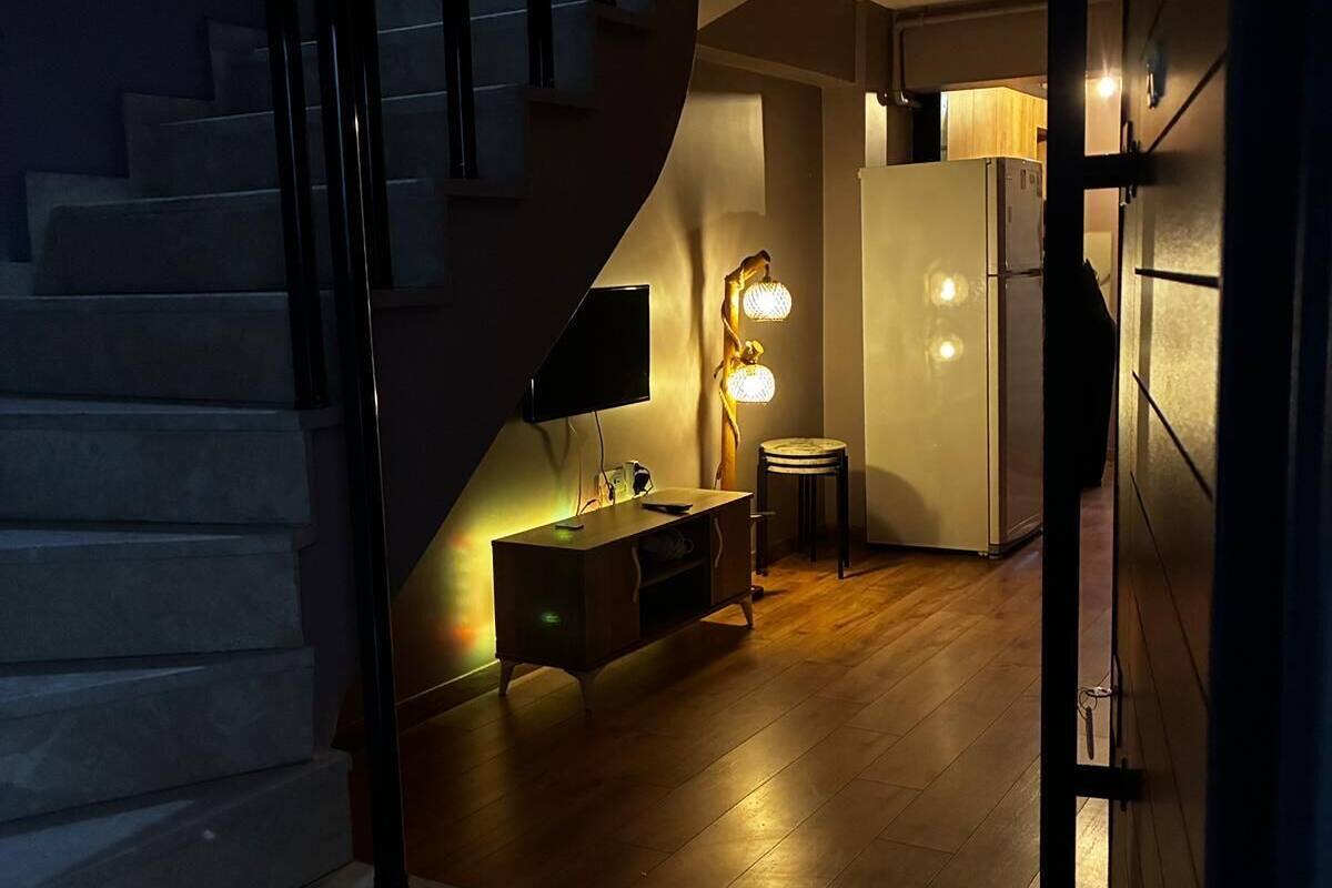 Un interior moderno con una escalera que conduce a una zona de cocina, una mesa de comedor y una barra.