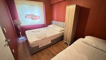 A bedroom with a bed, a wardrobe, a fan, and a wall-mounted projector displaying a car.