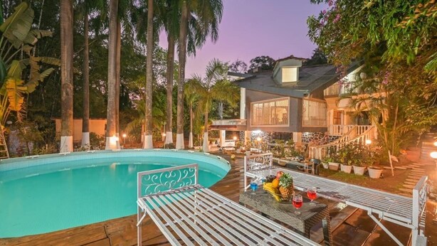 A pool with lounge chairs, a sign, and a house with a balcony.