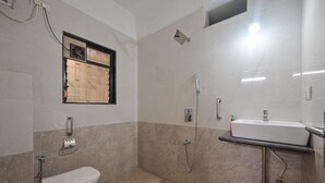 A bathroom with a toilet, a shower, a sink, and a window.