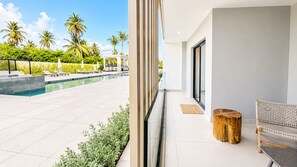 A modern hotel room with a pool, palm trees, and a view of the outdoors. - Born | 2BR ground floor with direct pool access (Bavaro)