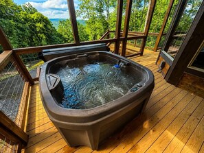 A hot tub on a wooden deck with a view of trees and hills. - 4-Bedroom Sevierville Cabin with Indoor Pool, Hot Tub & Game Room (Sevierville)