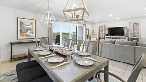 Un coin repas avec une table dressée pour quatre personnes, un canapé, un téléviseur et un balcon avec vue.