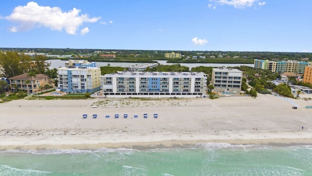 Un hôtel en bord de mer composé de plusieurs bâtiments, doté d’une plage de sable et offrant une vue sur l’océan.