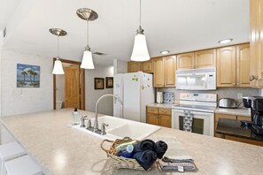 A modern kitchen with wooden cabinets, stainless steel appliances, and pendant lighting. - Holiday Villas 2 Unit 206 (Indian Shores)