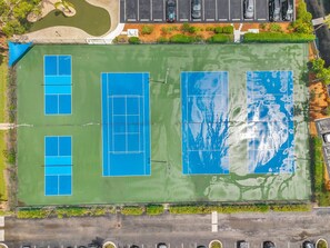 An aerial view of a tennis court complex with multiple courts, a parking area, and surrounding greenery. - Comfortable 1 Bedroom with Intracoastal Water Views (Indian Shores)