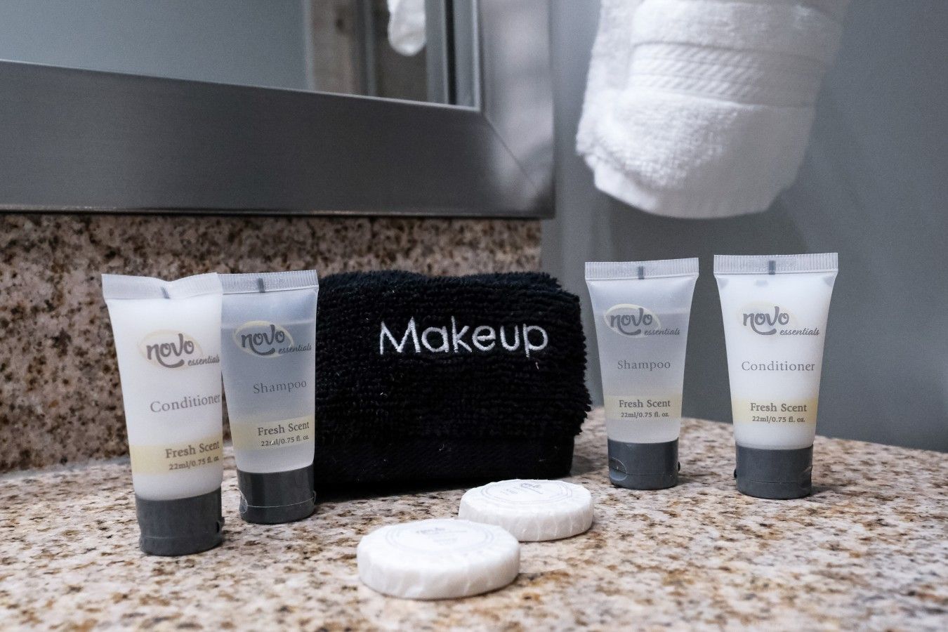 Toiletries including a black towel labeled 'Makeup' and several tubes of 'novo essentials' shampoo and conditioner.