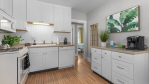Una cocina moderna con armarios blancos, estufa integrada y cafetera.