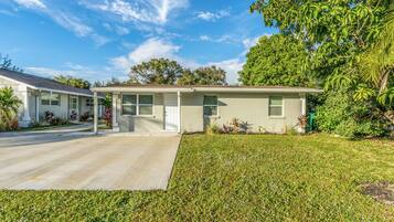 A single-story house with a front porch, a driveway, and a well-maintained lawn.